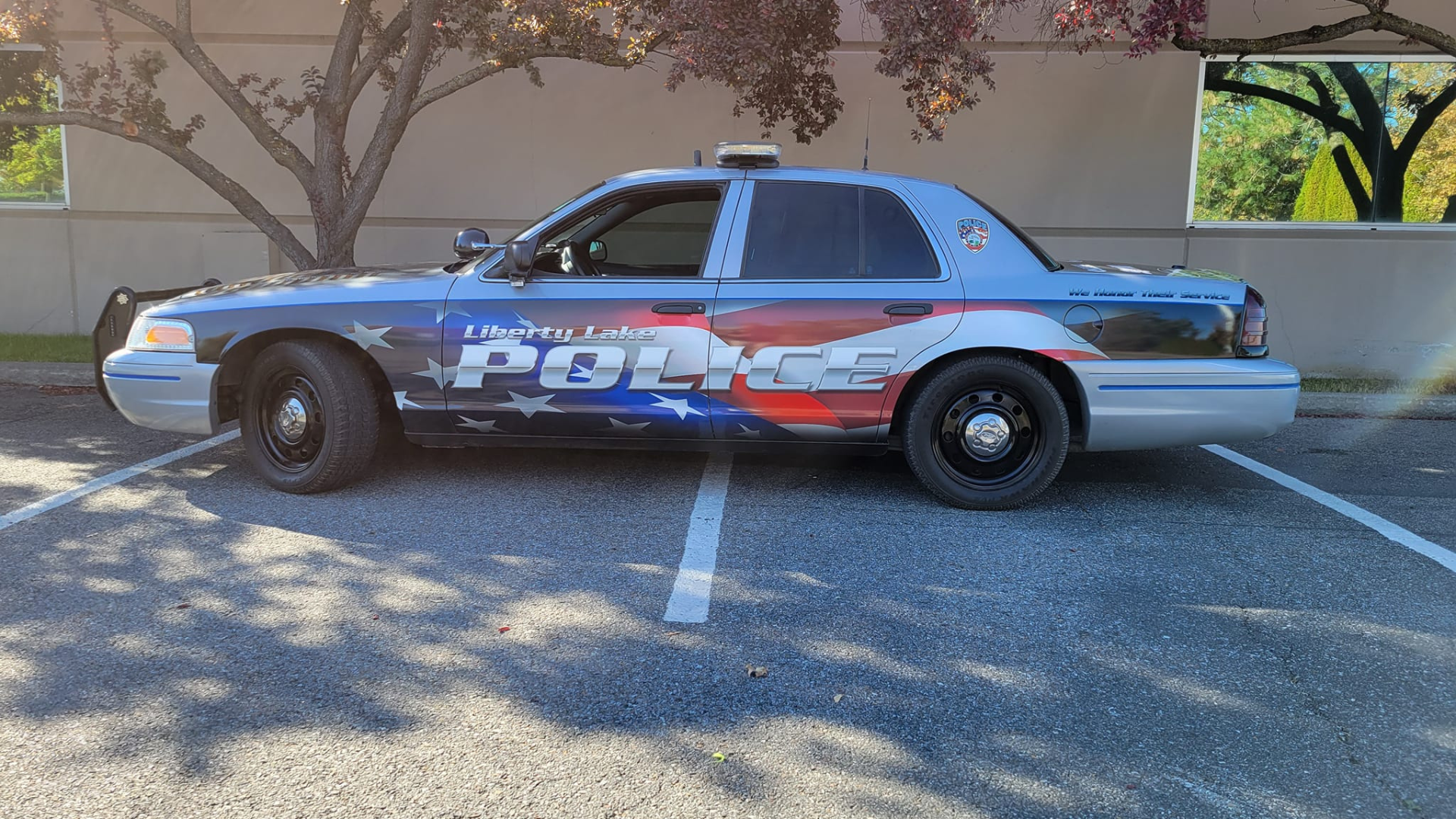 Side profile of a Liberty Lake Police vehicle parked in a parking lot, highlighting the patriotic graphics on the car.