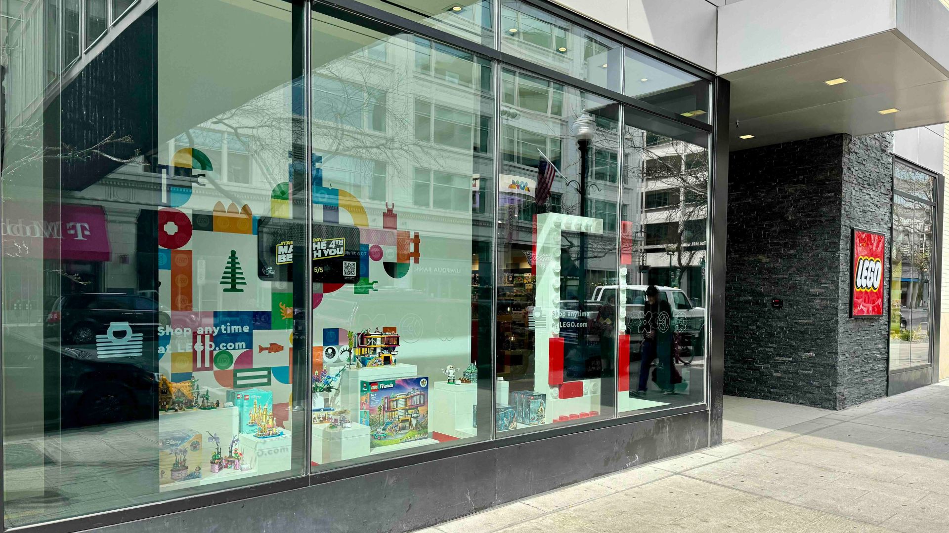 Storefront of LEGO retail shop in Downtown Spokane, showcasing colorful displays of LEGO sets and company branding in window.