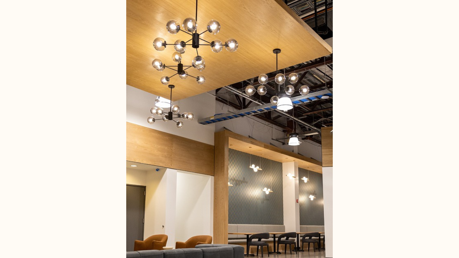Stylish and modern interior of a coworking space illuminated by a cluster of spherical light bulbs hanging from a wooden ceiling, providing a warm glow.